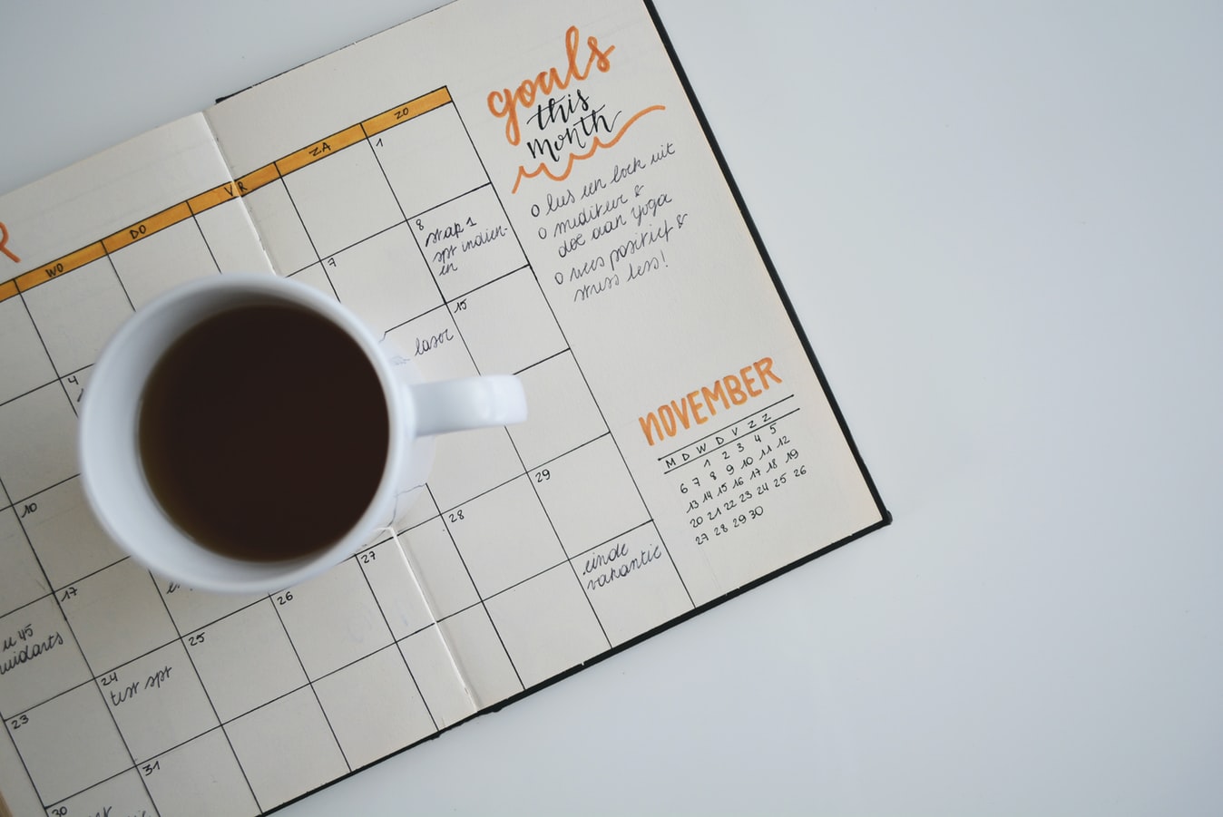 A coffee cup on a planner with goals written out. 