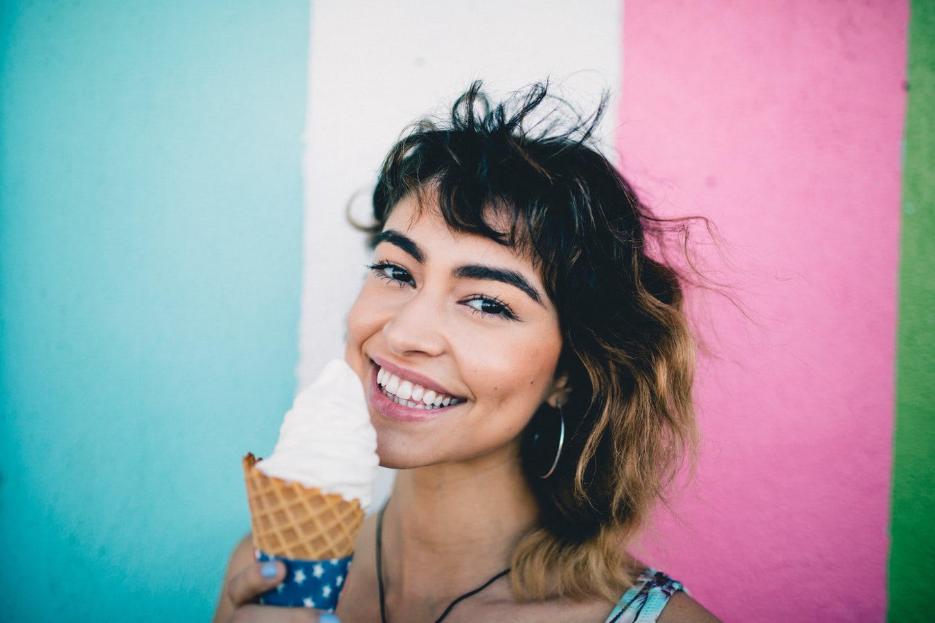 A woman smiles with a cone of ice cream.