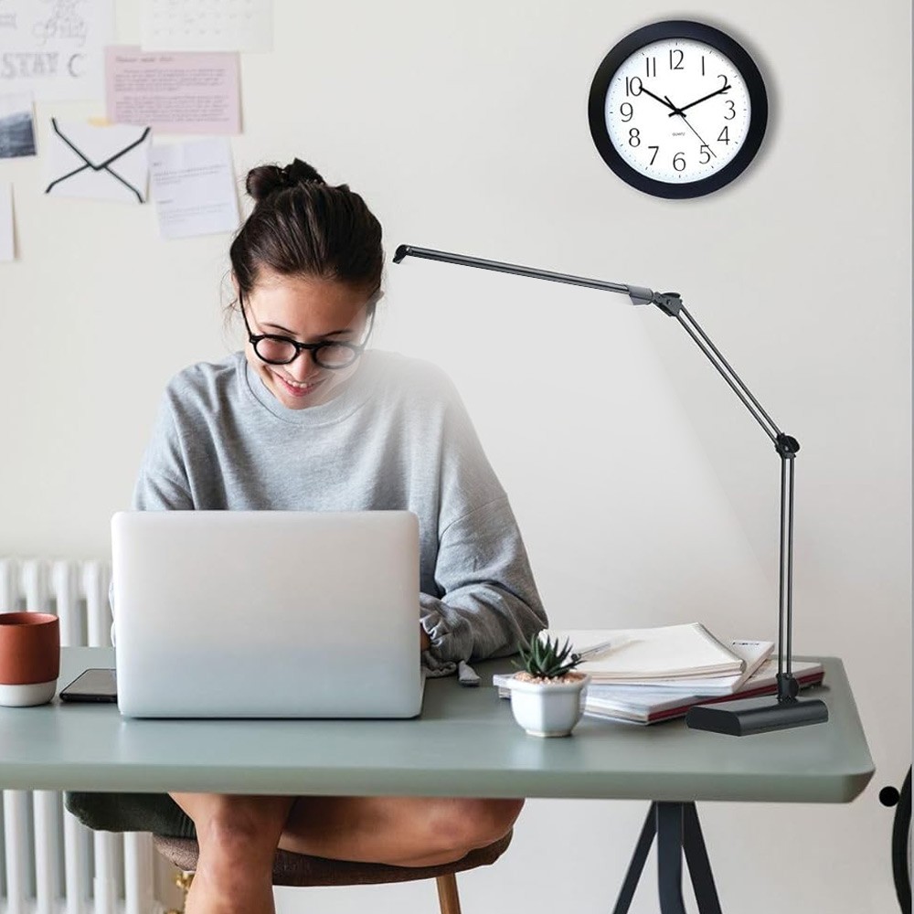 Woman working on laptop with LED desk light